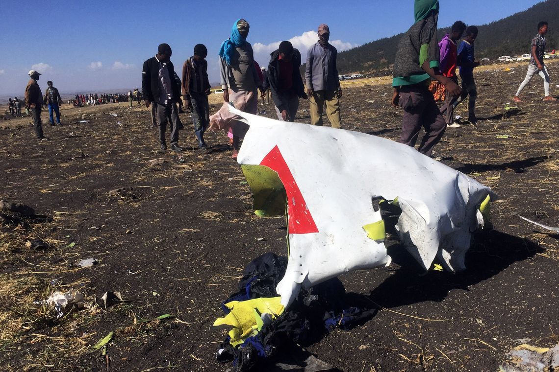 People walk past a part of the wreckage at the scene of the Ethiopian Airlines Flight ET 302 plane crash, near the town of Bishoftu, southeast of Addis Ababa, Ethiopia March 10, 2019. REUTERS/Tiksa Negeri