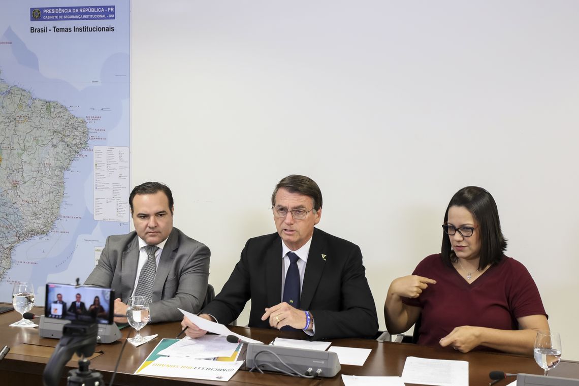 O presidente Jair Bolsonaro faz transmissão ao vivo ao lado do ministro da Secretaria-Geral da Presidência, Jorge Francisco, e da intérprete de libras, Elizângela Castelo Branco.