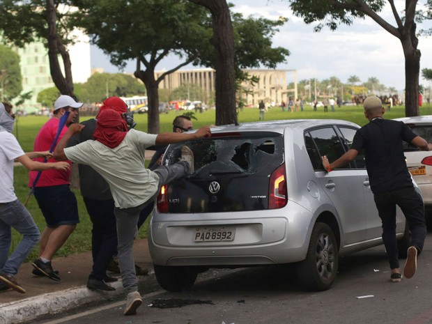 Manifestantes quebram um carro estacionado na Esplanada dos Ministérios, em Brasília, durante protesto contra a PEC 55, que limita os gastos públicos para os próximos 20 anos (Foto: Eraldo Peres/AP)